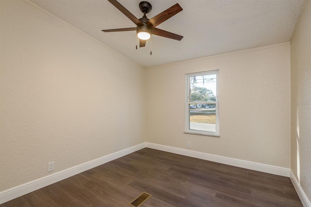 6707 Celeste Lane New Port Richey, FL 34653 - Photo 17 of 21 an empty room with wooden floor ceiling fan and windows