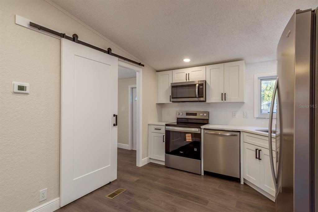 6707 Celeste Lane New Port Richey, FL 34653 - Photo 7 of 21 a kitchen with stainless steel appliances granite countertop a refrigerator and a stove top oven
