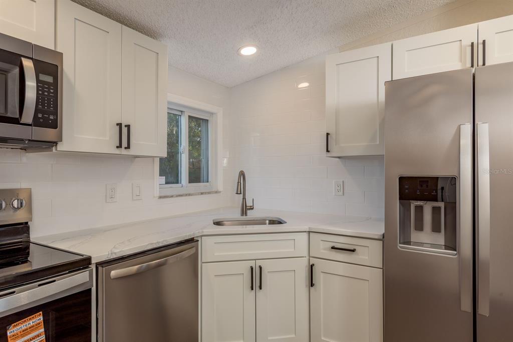 6707 Celeste Lane New Port Richey, FL 34653 - Photo 9 of 21 a kitchen with a sink stainless steel appliances and white cabinets