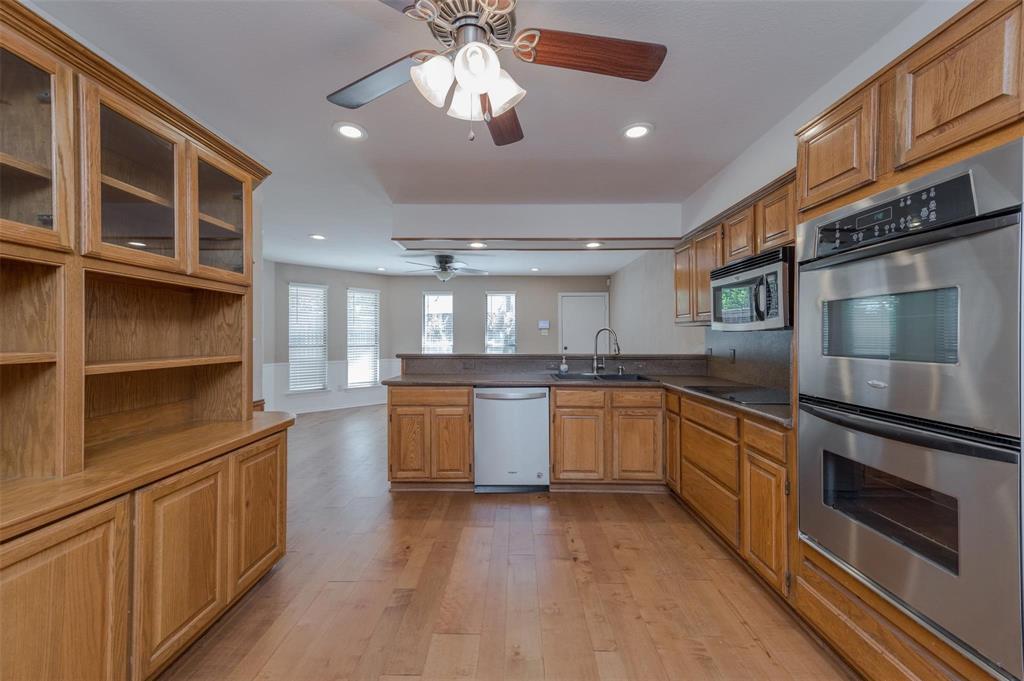 1106 Derby Run Carrollton, TX 75007 - Photo 11 of 26 a kitchen with stainless steel appliances granite countertop a refrigerator a sink dishwasher a stove with wooden cabinets and floor