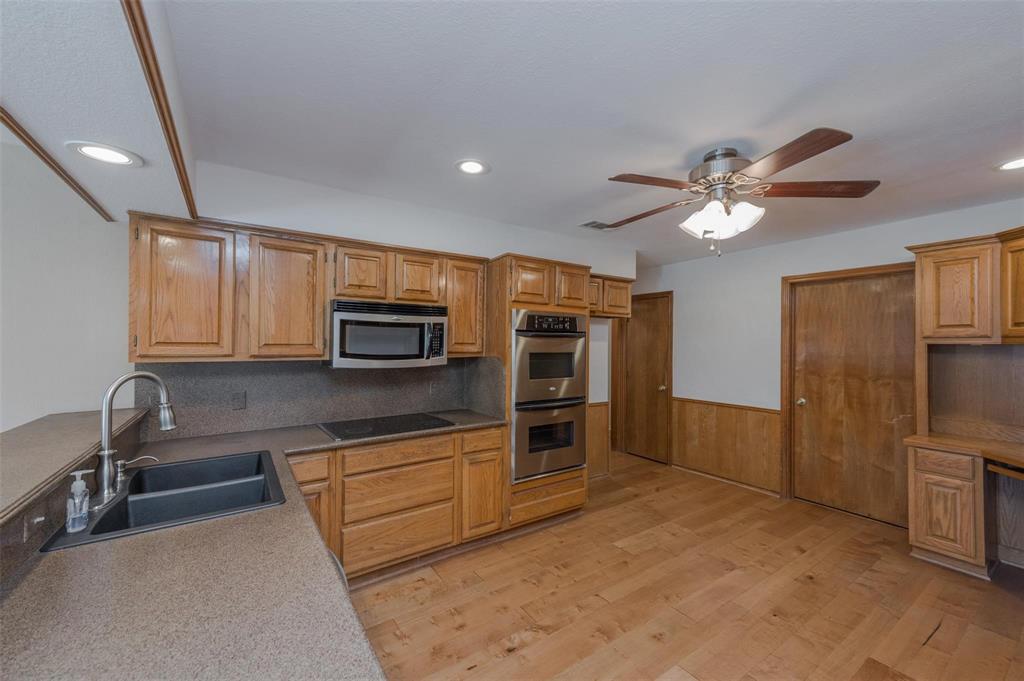 1106 Derby Run Carrollton, TX 75007 - Photo 12 of 26 a kitchen with stainless steel appliances granite countertop a refrigerator oven a sink dishwasher and white cabinets with wooden floor