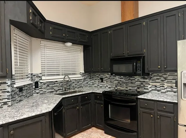 a kitchen with granite countertop stainless steel appliances a sink stove and cabinets