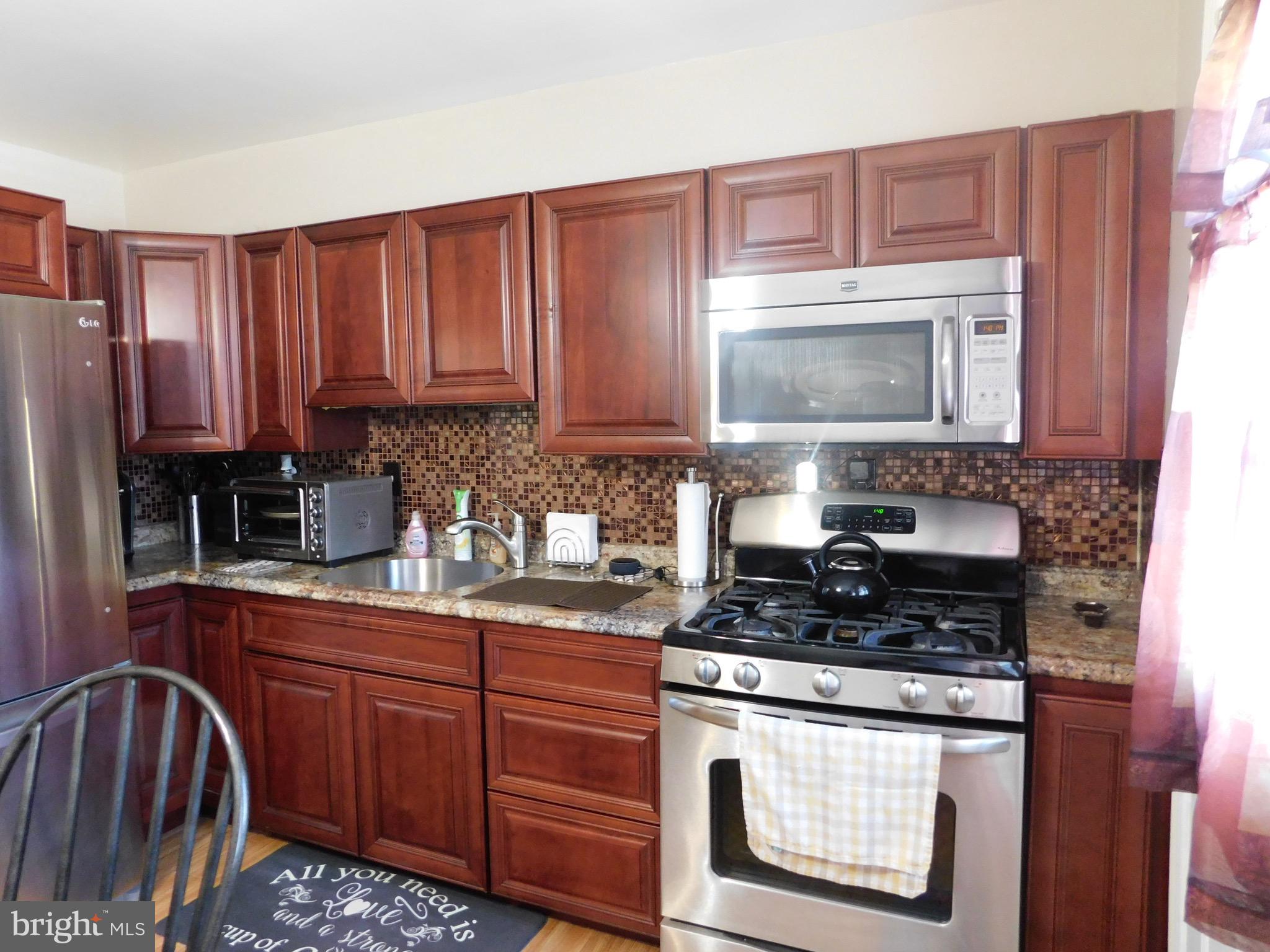 1333 Deanwood Road Baltimore, MD 21234 - Photo 1 of 40 a kitchen with granite countertop a stove top oven microwave and cabinets