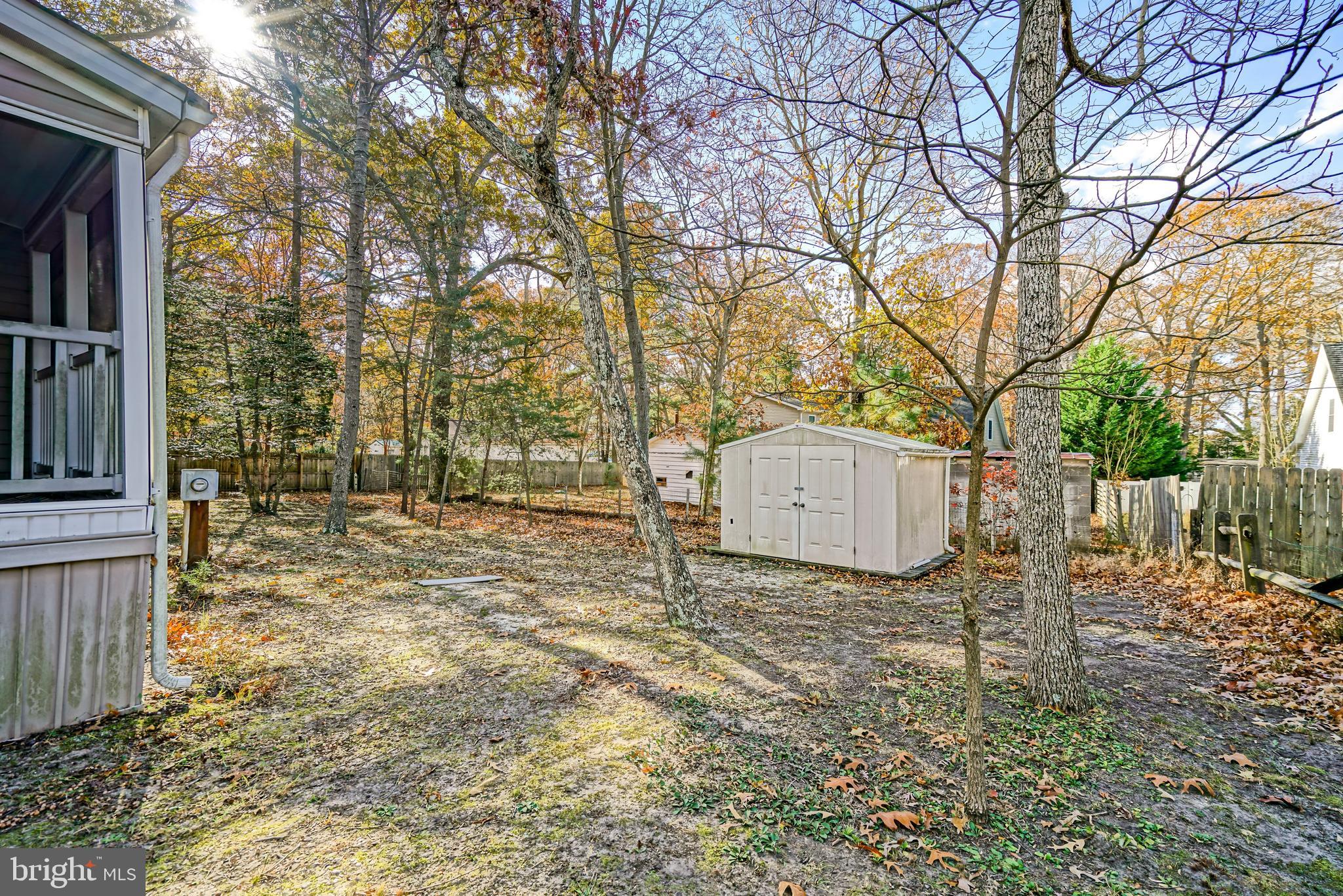 22916 Pine Road Lewes, DE 19958 - Photo 27 of 35 a backyard of a house with a large tree and wooden fence