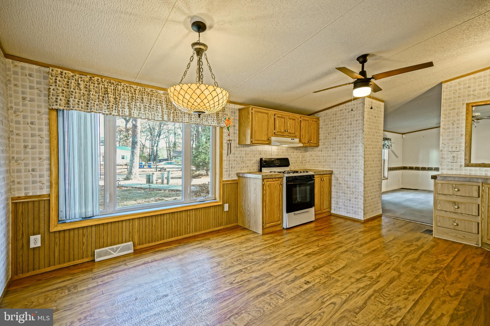 22916 Pine Road Lewes, DE 19958 - Photo 10 of 35 a view of a kitchen with a stove wooden cabinets and a floor to ceiling window