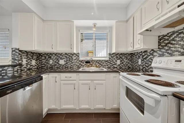 a kitchen with granite countertop white cabinets and white appliances