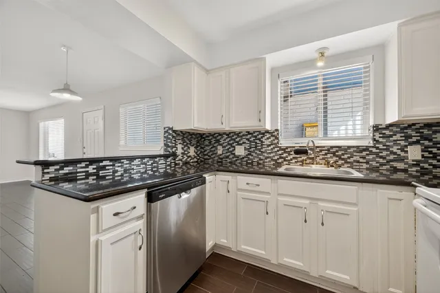 a kitchen with granite countertop a sink stove and cabinets