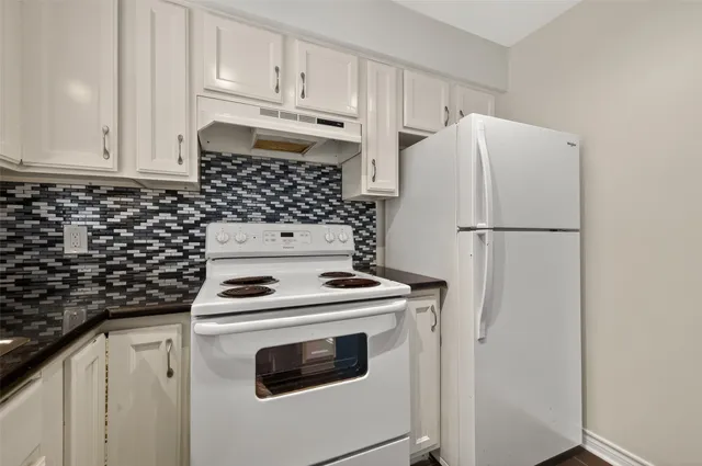 a kitchen with refrigerator a stove and white cabinets