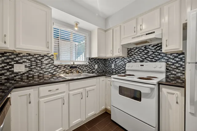 a kitchen with granite countertop white cabinets and white appliances