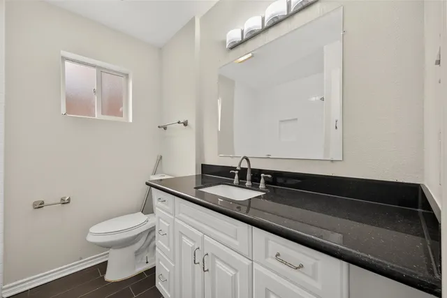 a bathroom with a granite countertop sink a toilet and a mirror