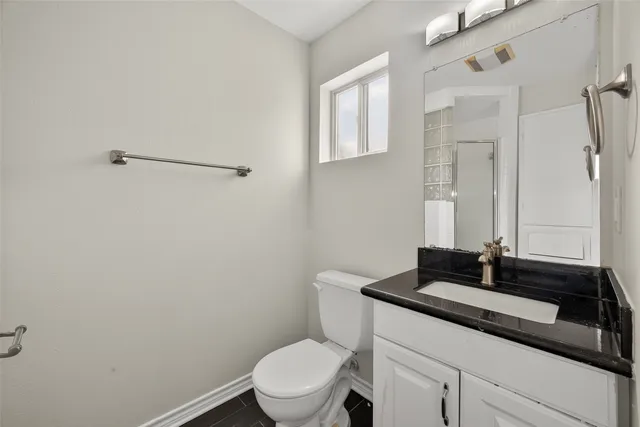 a bathroom with a granite countertop sink a toilet and a mirror