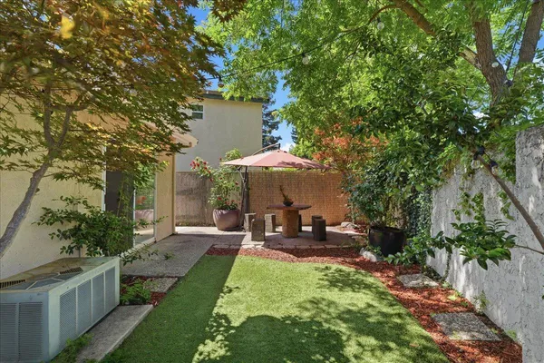 a backyard of a house with table and chairs under an umbrella