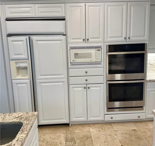 a kitchen with white cabinets and a refrigerator