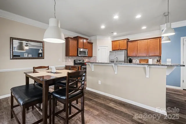 a kitchen with stainless steel appliances granite countertop a sink a stove a dining table and chairs