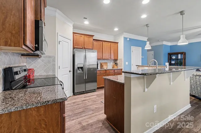 a kitchen with stainless steel appliances granite countertop a refrigerator a stove and a sink