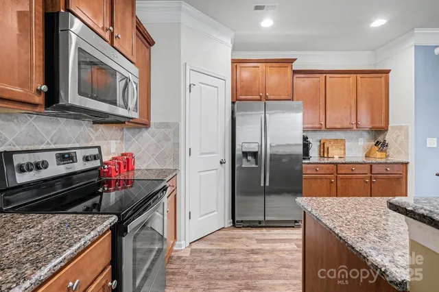 a kitchen with stainless steel appliances granite countertop a refrigerator sink and stove