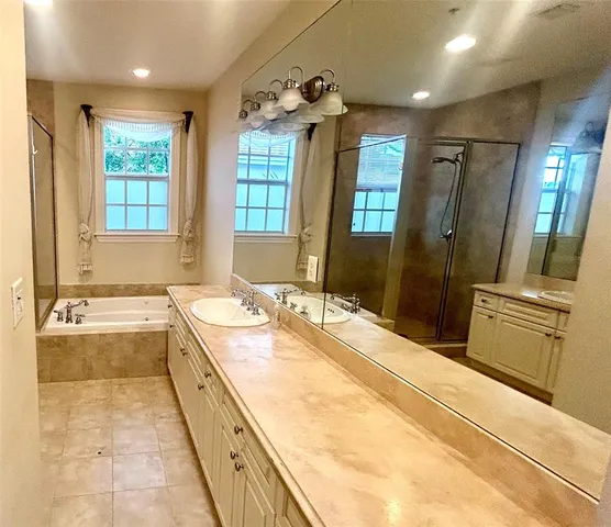 a bathroom with a granite countertop tub sink and mirror