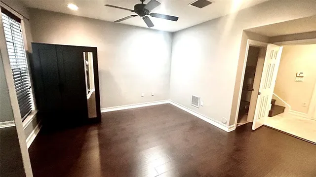 an empty room with wooden floor cabinet and windows