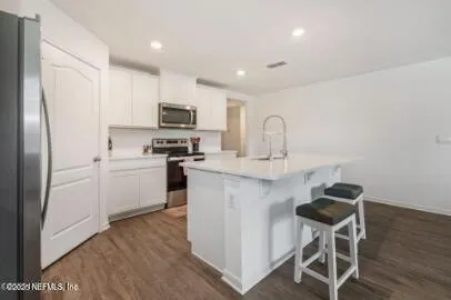 a kitchen with kitchen island a white counter top space stainless steel appliances and cabinets