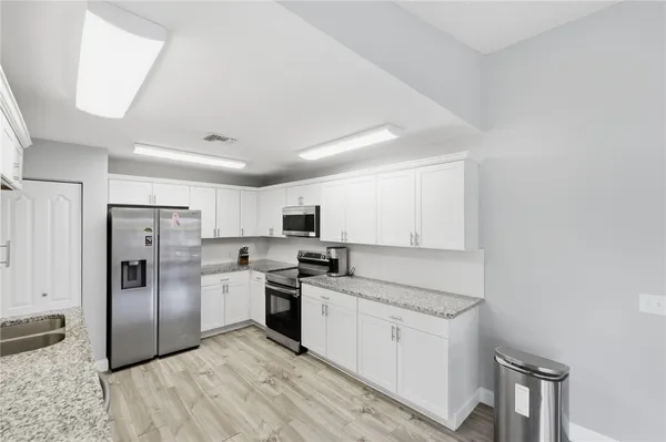 a kitchen with white cabinets and stainless steel appliances