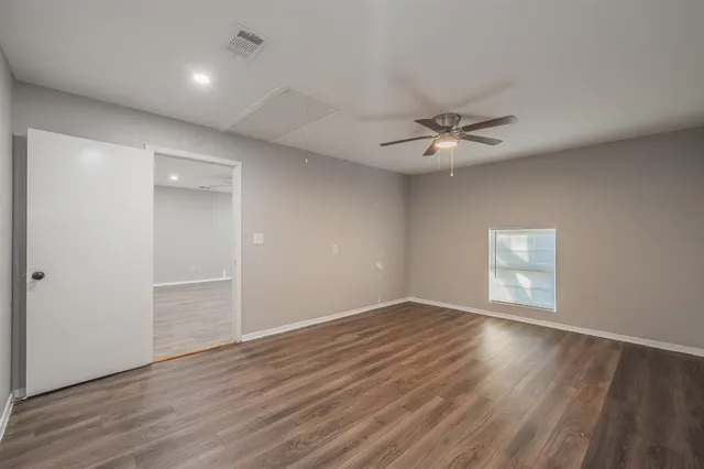 an empty room with wooden floor and ceiling fan