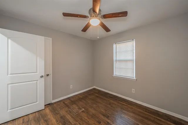 an empty room with wooden floor chandelier fan and windows