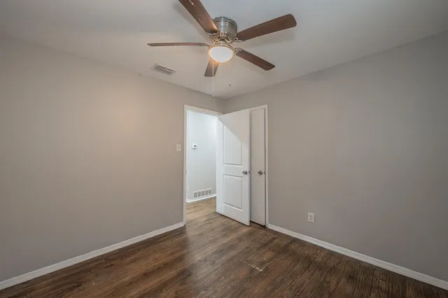 an empty room with wooden floor and ceiling fan