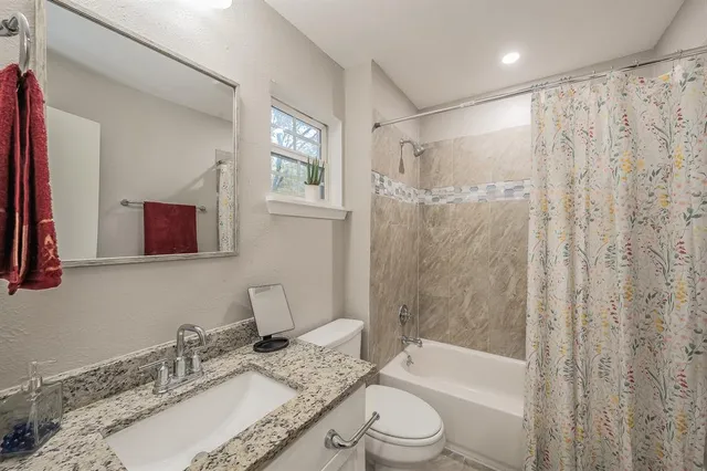a bathroom with a granite countertop sink toilet and shower