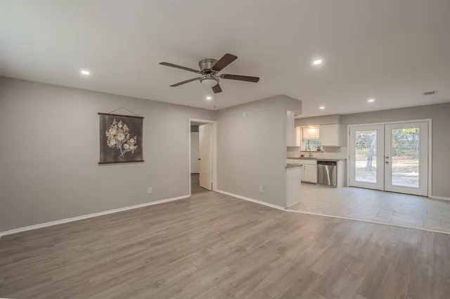 a view of an empty room with window and wooden floor