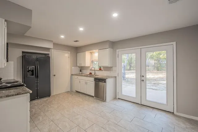 a kitchen with a refrigerator and white cabinets