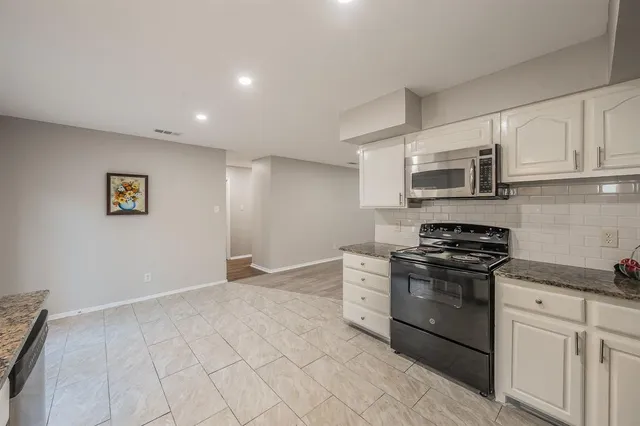 a kitchen with stainless steel appliances granite countertop a stove a sink and a microwave
