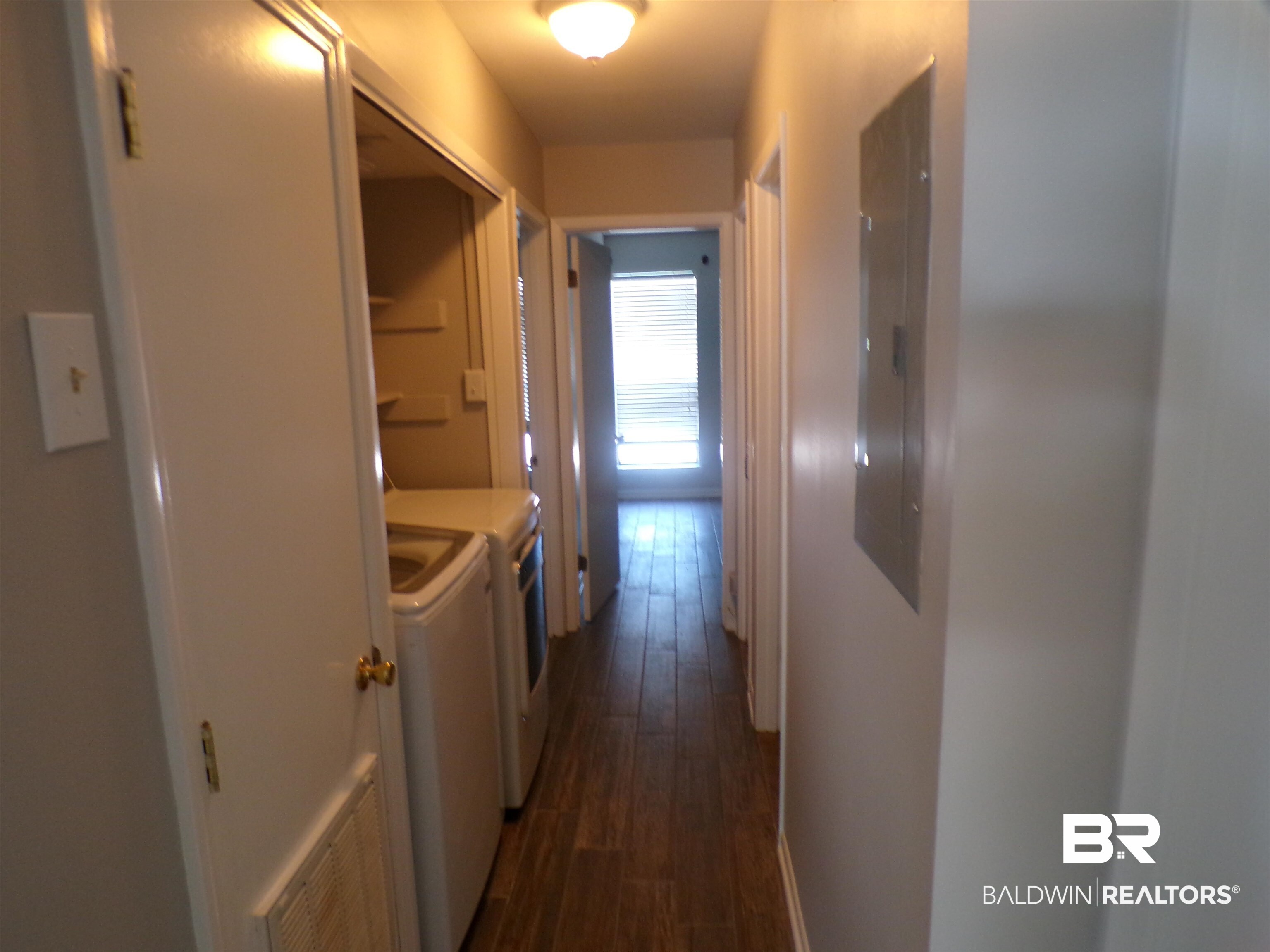 1152 North Alston Street, Unit 1152 Foley, AL 36535 - Photo 10 of 16 Hallway featuring wood-finish flooring, light neutral wall paint, and a built-in laundry area with shelving