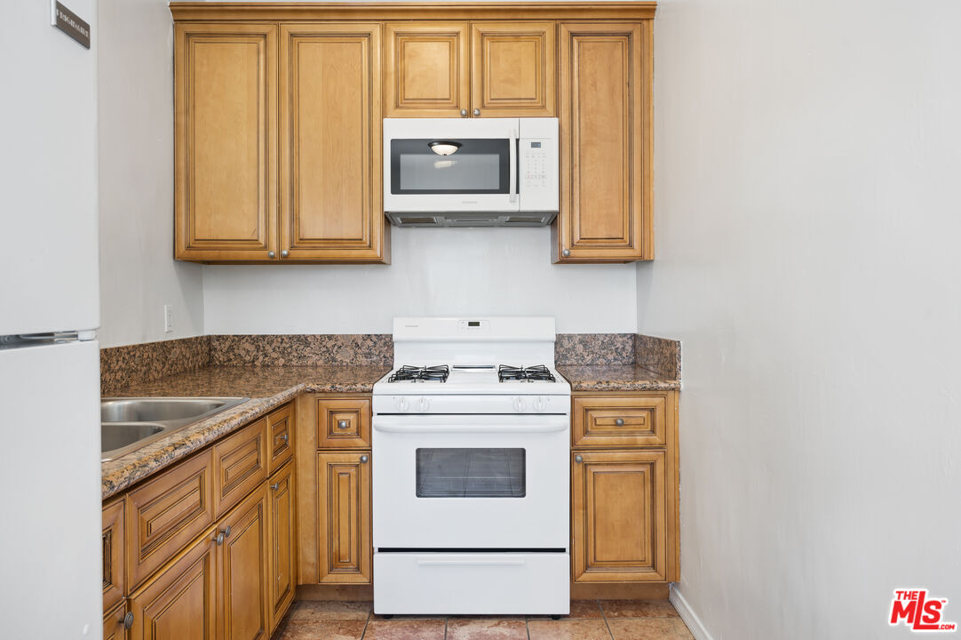 1044 North Bonnie Brae Street, Unit 202 Los Angeles, CA 90026 - Photo 3 of 6 a kitchen with stainless steel appliances granite countertop white cabinets and a stove top oven