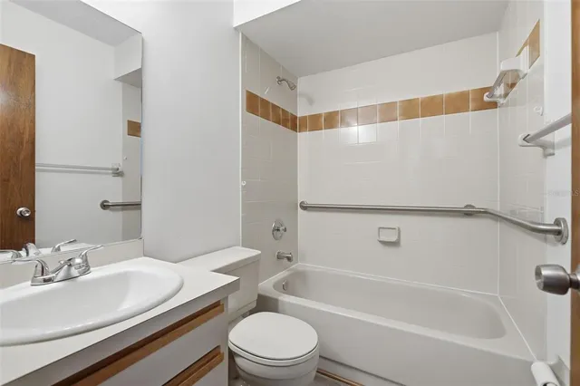 a bathroom with a granite countertop bathtub shower sink mirror vanity and toilet