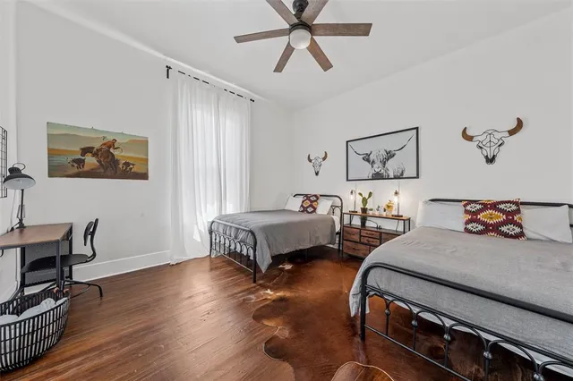 an empty room with wooden floor chandelier fan and windows