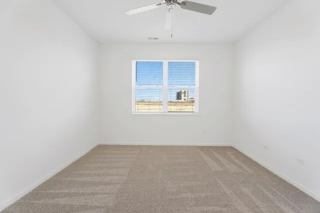 an empty room with a ceiling fan and a window
