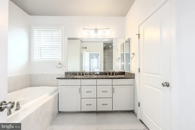 a bathroom with a granite countertop sink a toilet a mirror a bathtub and shower