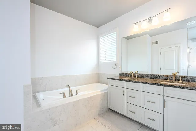 a bathroom with a granite countertop sink mirror and bathtub