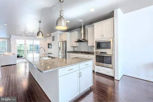 a large kitchen with granite countertop a stove oven and a wooden floor