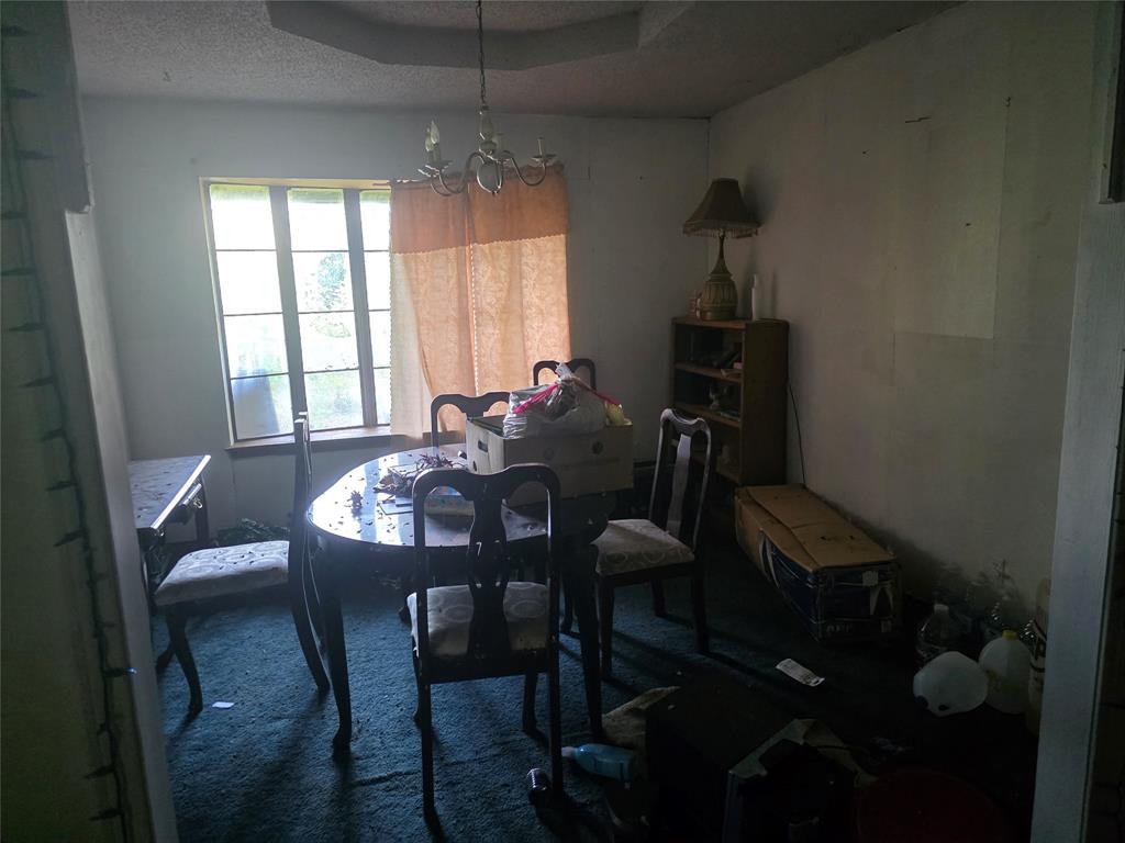 7442 County Road 4812 Commerce, TX 75428 - Photo 8 of 15 Dining room featuring carpet, a chandelier, and a textured ceiling