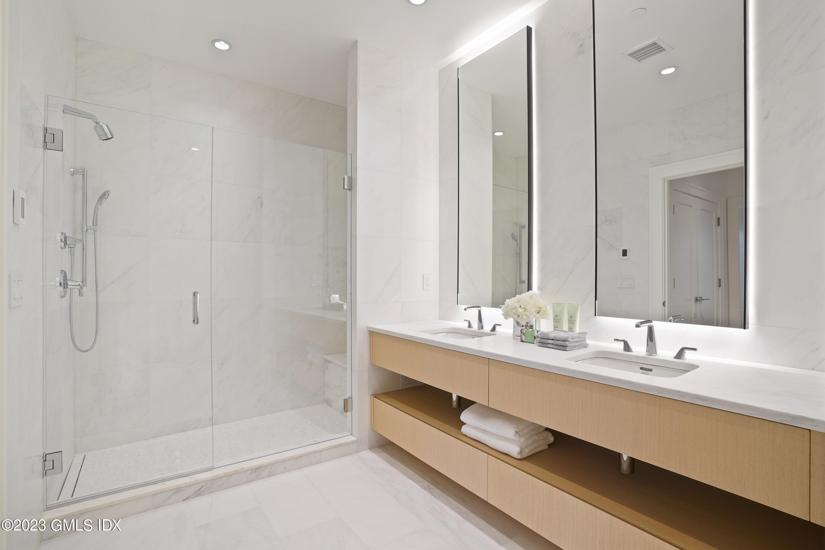 89 River Road, Unit 302 Cos Cob, CT 06807 - Photo 7 of 24 a bathroom with a double vanity sink a large mirror and shower