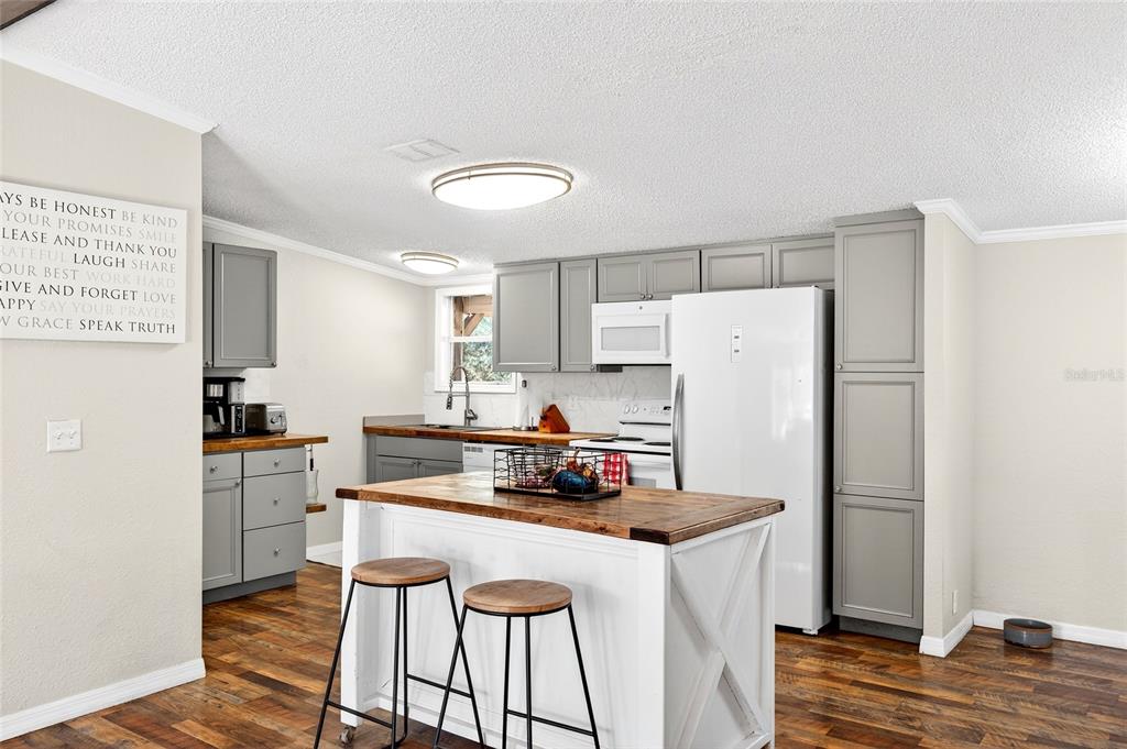 17087 Southwest 27 Street Dunnellon, FL 34432 - Photo 11 of 53 a kitchen with a refrigerator a stove a sink and white cabinets with wooden floor