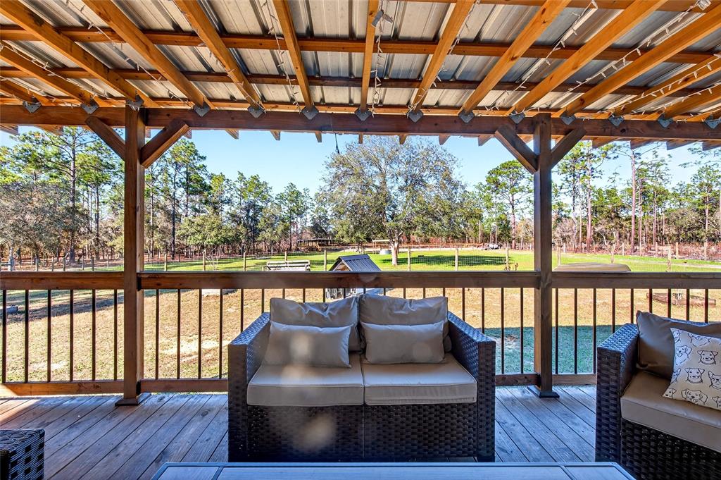17087 Southwest 27 Street Dunnellon, FL 34432 - Photo 29 of 53 a balcony view with couches and wooden floor with trees in the back
