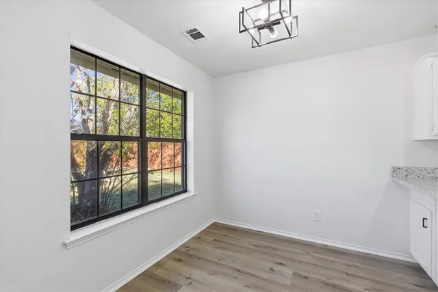 an empty room with chandelier fan and windows