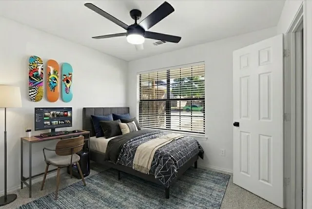 a bedroom with a bed a workstation with paintings on the wall