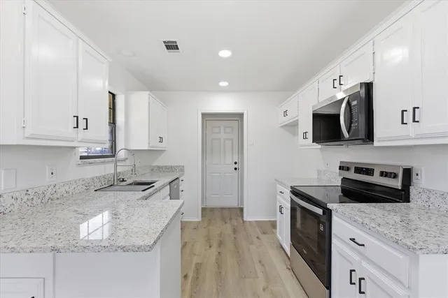 a kitchen with granite countertop a sink stove and cabinets