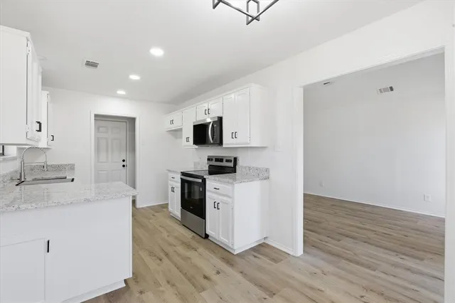 a kitchen with granite countertop white cabinets and white appliances