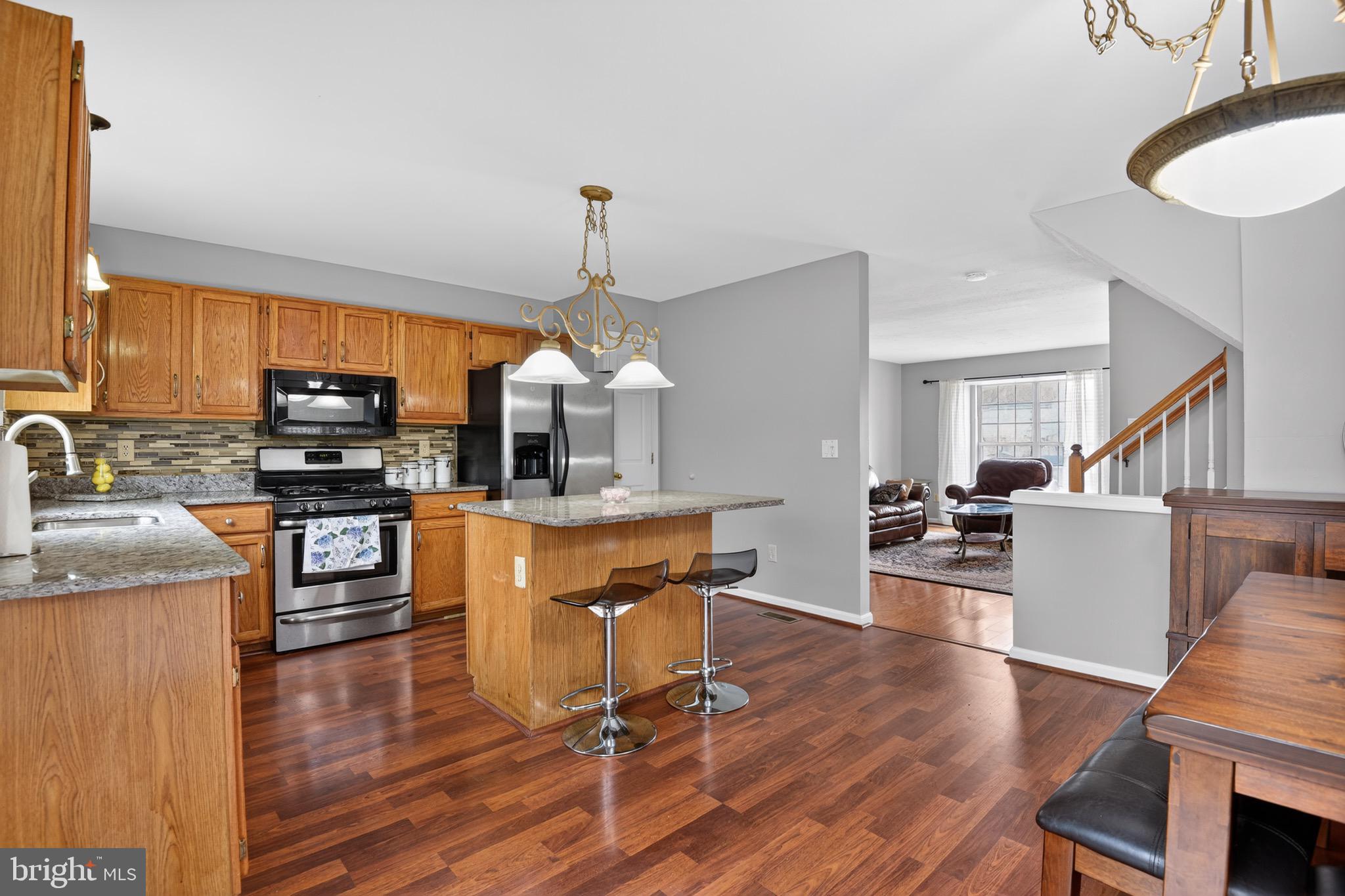 226 Finch Way Newark, DE 19702 - Photo 12 of 30 a kitchen with stainless steel appliances granite countertop a stove top oven a sink dishwasher a dining table and chairs with wooden floor