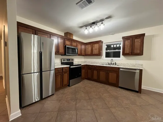 a kitchen with stainless steel appliances granite countertop a refrigerator sink and stove