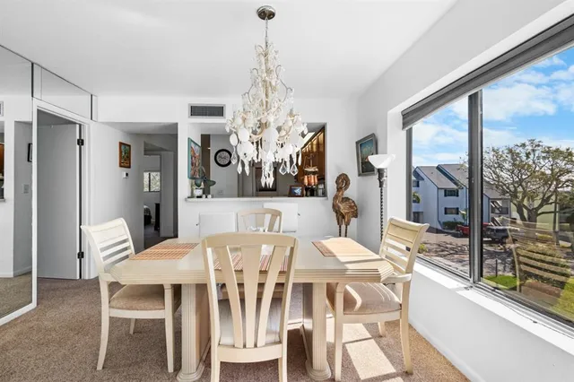 a view of a dining room with furniture a chandelier and large windows